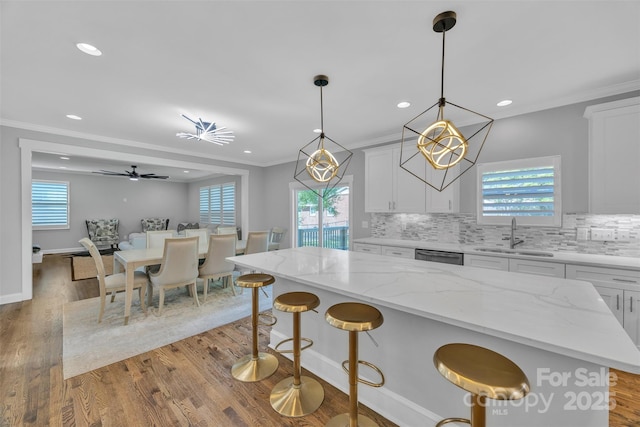 kitchen featuring recessed lighting, a sink, white cabinetry, wood finished floors, and tasteful backsplash