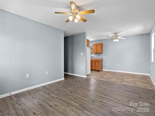 unfurnished living room with baseboards, a ceiling fan, and wood finished floors