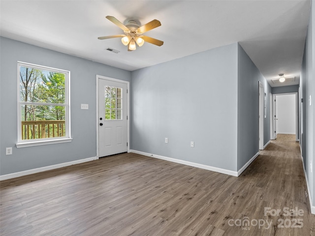 interior space featuring baseboards, ceiling fan, wood finished floors, and visible vents
