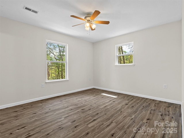 spare room featuring visible vents, wood finished floors, and a wealth of natural light