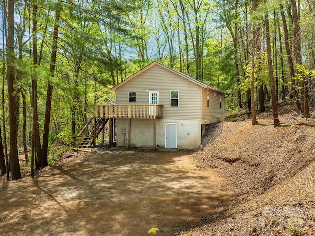 exterior space featuring stairs, a deck, and a forest view