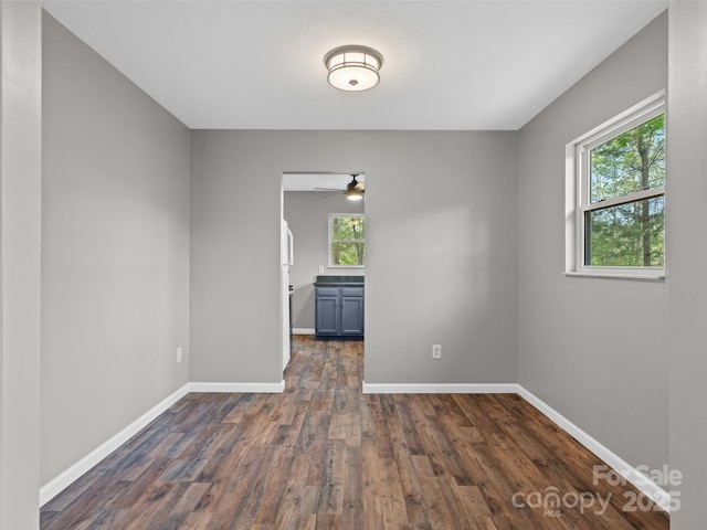 spare room featuring baseboards, a ceiling fan, and dark wood-type flooring