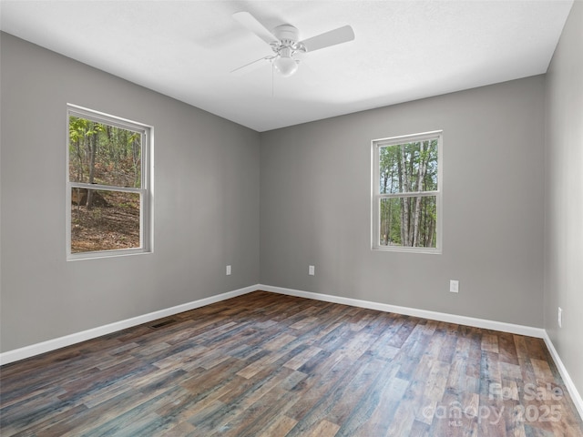 empty room with a ceiling fan, baseboards, and dark wood-style floors