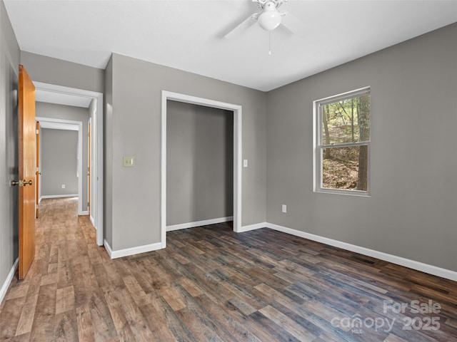 unfurnished bedroom featuring dark wood-style flooring, baseboards, a ceiling fan, and a closet
