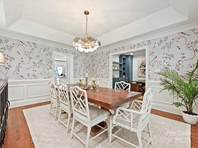 dining space featuring a raised ceiling, wallpapered walls, and a chandelier