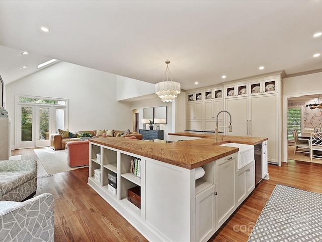 kitchen with a sink, open floor plan, a notable chandelier, and butcher block counters
