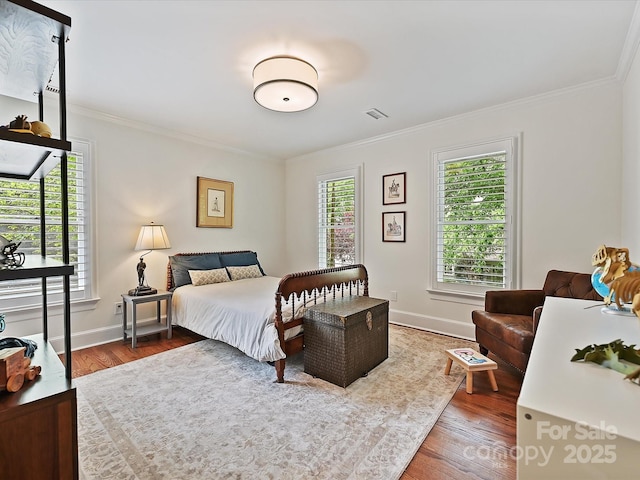 bedroom with baseboards, ornamental molding, and wood finished floors