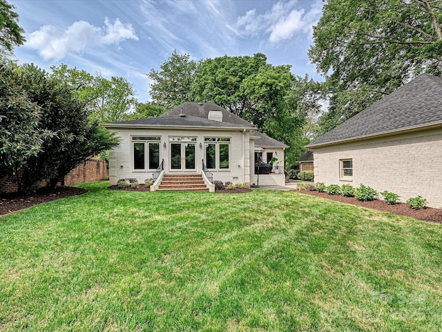 back of property featuring a yard, brick siding, french doors, and a shingled roof