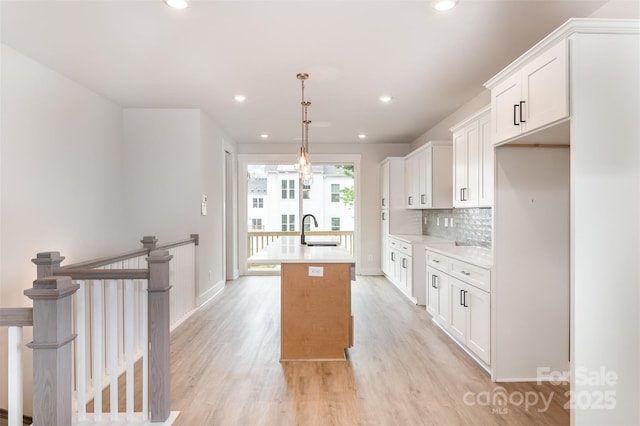 kitchen featuring light countertops, recessed lighting, a center island with sink, and light wood-style flooring
