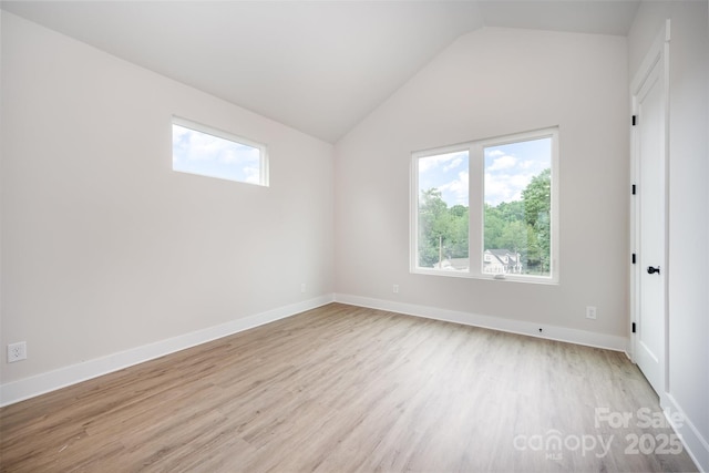 interior space featuring light wood finished floors, a healthy amount of sunlight, and vaulted ceiling
