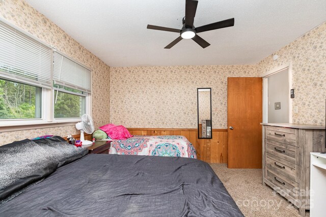 3603 Ken Mcentire Rd, Lawndale, NC 28090 - bedroom with wainscoting, wood walls, wallpapered walls, light colored carpet, and ceiling fan