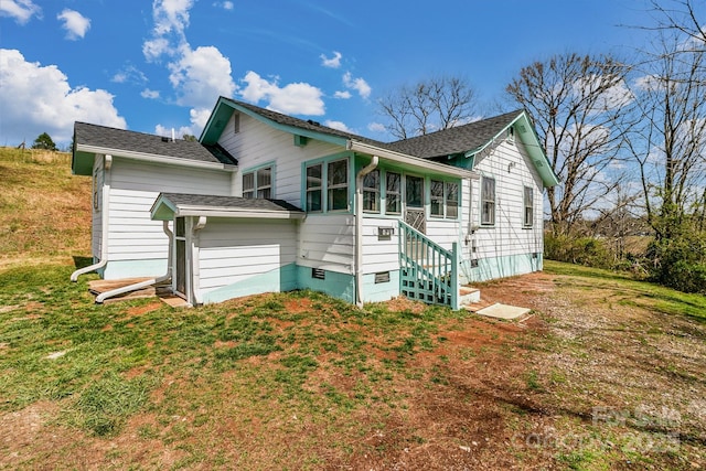 rear view of property featuring crawl space, roof with shingles, and a yard