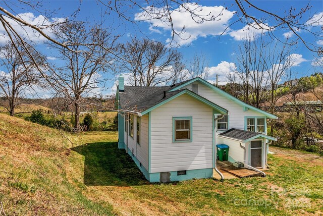 view of side of property with a yard, a shingled roof, a chimney, and crawl space