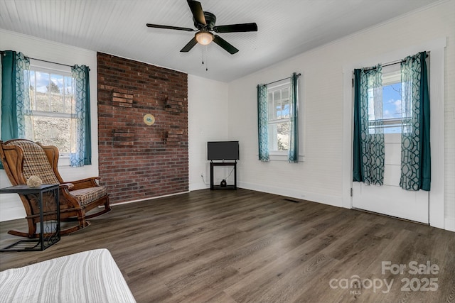 sitting room with brick wall, a ceiling fan, and wood finished floors