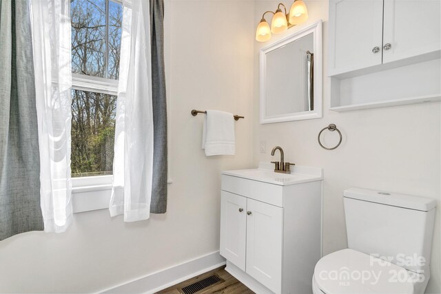 bathroom featuring visible vents, toilet, vanity, and a healthy amount of sunlight