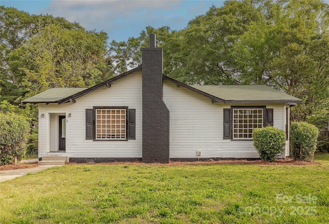 view of front facade with a chimney and a front yard