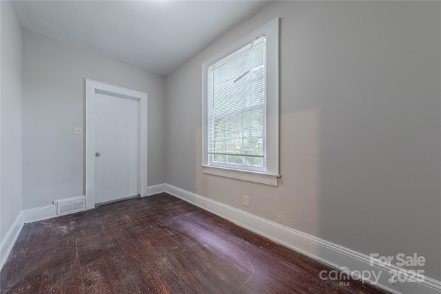 spare room with dark wood finished floors, baseboards, and visible vents