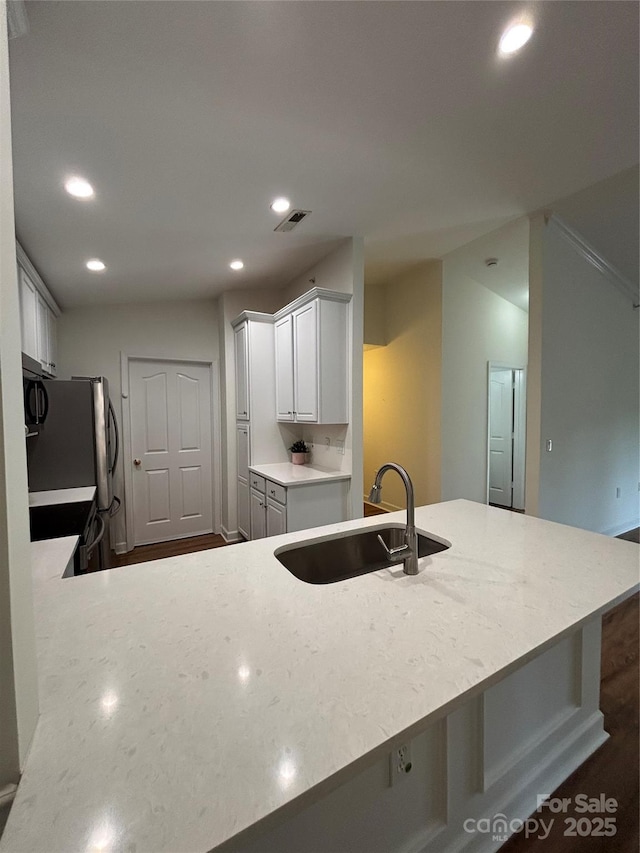 kitchen featuring visible vents, a sink, freestanding refrigerator, a peninsula, and recessed lighting