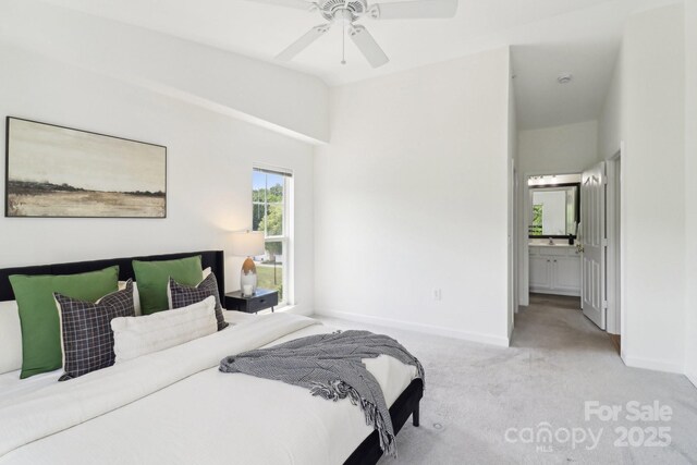 carpeted bedroom featuring baseboards, vaulted ceiling, ceiling fan, and ensuite bath
