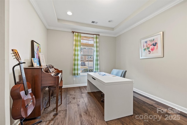 office area with crown molding, a tray ceiling, baseboards, dark wood-type flooring, and visible vents