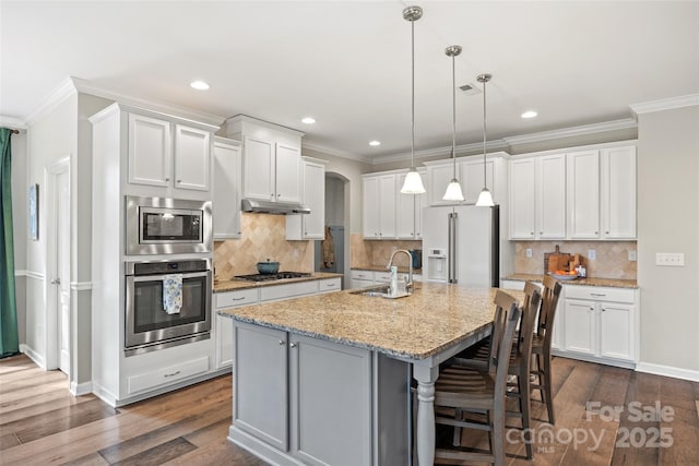 kitchen featuring a sink, arched walkways, dark wood-type flooring, crown molding, and appliances with stainless steel finishes