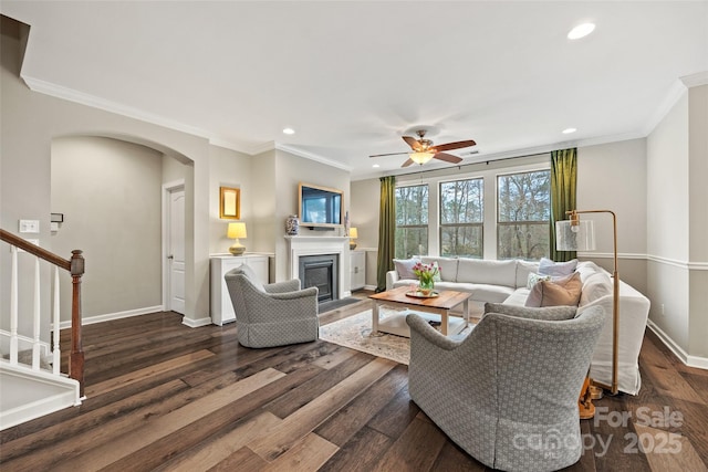 living room with arched walkways, dark wood-style flooring, crown molding, and recessed lighting