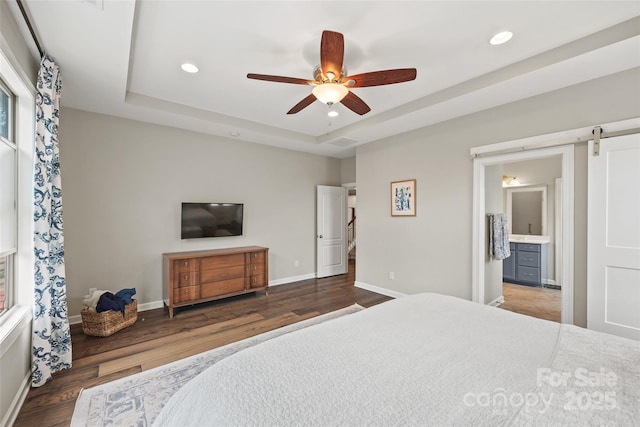 bedroom with a tray ceiling, wood finished floors, and recessed lighting