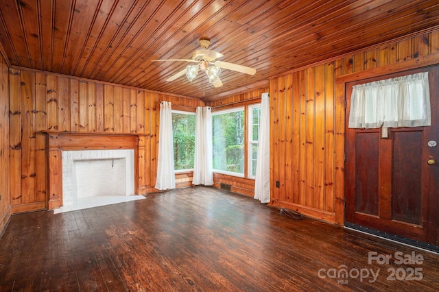 unfurnished living room featuring wooden walls, ceiling fan, wood-type flooring, wooden ceiling, and visible vents