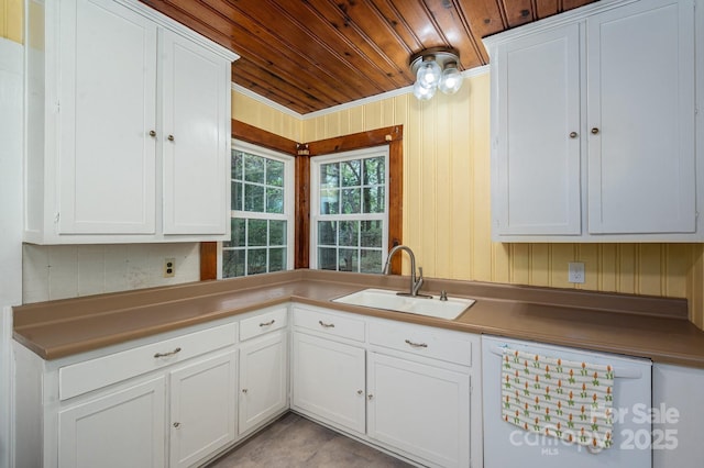 kitchen with white dishwasher, a sink, white cabinets, and wooden ceiling