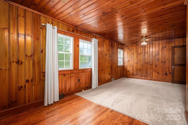 spare room with light wood-type flooring, ceiling fan, a healthy amount of sunlight, and wooden ceiling