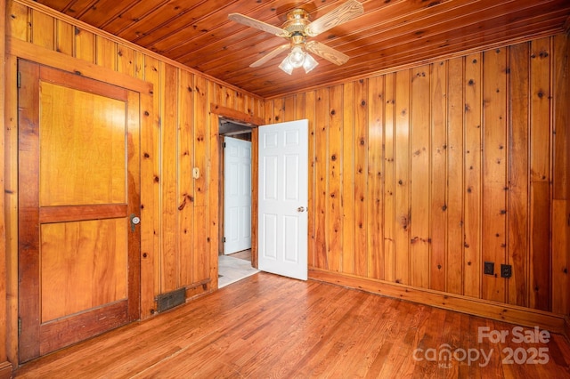 unfurnished bedroom with wooden walls, wooden ceiling, and wood finished floors