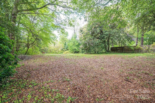 view of yard with fence and a wooded view