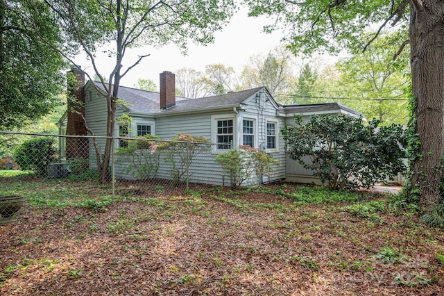 back of property with fence, a chimney, and roof with shingles