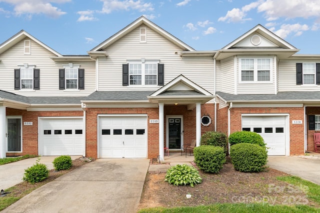 townhome / multi-family property with an attached garage, brick siding, and driveway