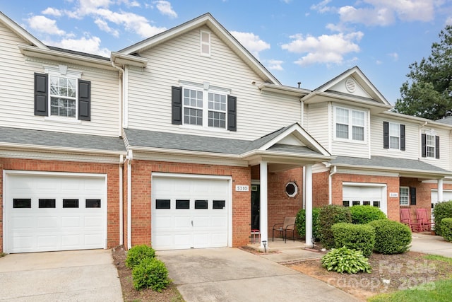 multi unit property with a garage, brick siding, and driveway