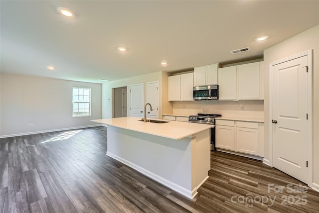 2107 Columbidae Ln, Gastonia, NC 28052 - kitchen with stainless steel appliances, an island with sink, white cabinets, dark wood finished floors, and recessed lighting