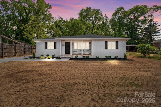 ranch-style home with brick siding, fence, and a front lawn