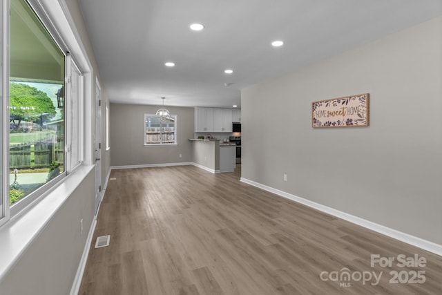 unfurnished living room featuring recessed lighting, baseboards, visible vents, and wood finished floors