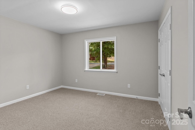 carpeted spare room featuring baseboards and visible vents