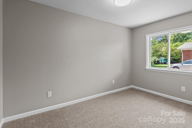 spare room with baseboards and carpet