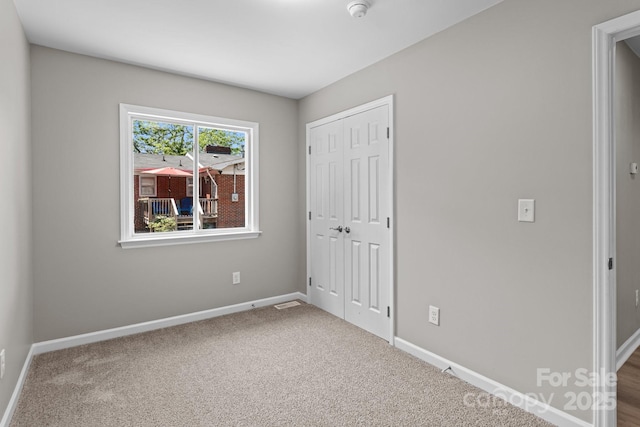 unfurnished bedroom with carpet flooring, baseboards, and a closet