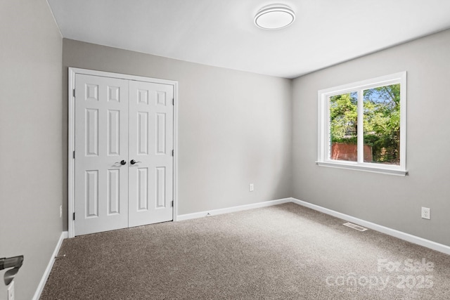 unfurnished bedroom featuring carpet floors, baseboards, visible vents, and a closet
