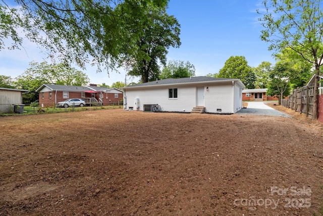 rear view of house featuring brick siding, central AC, fence, and entry steps