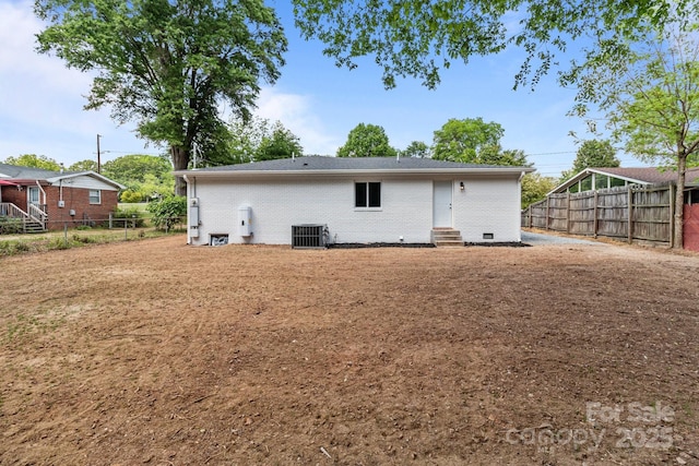 rear view of house with brick siding, fence, central AC unit, and entry steps