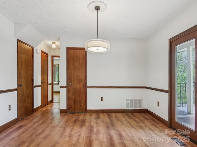 unfurnished dining area featuring light wood-type flooring, visible vents, and baseboards