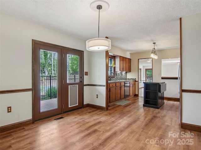 kitchen with brown cabinetry, light wood-style flooring, and baseboards