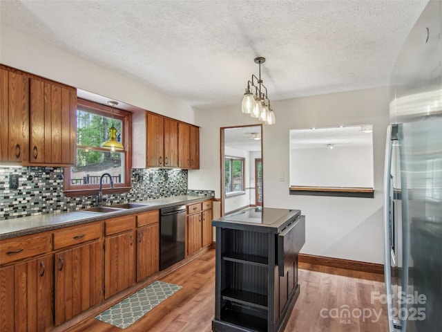 kitchen featuring backsplash, dishwasher, a sink, light wood-style floors, and brown cabinetry