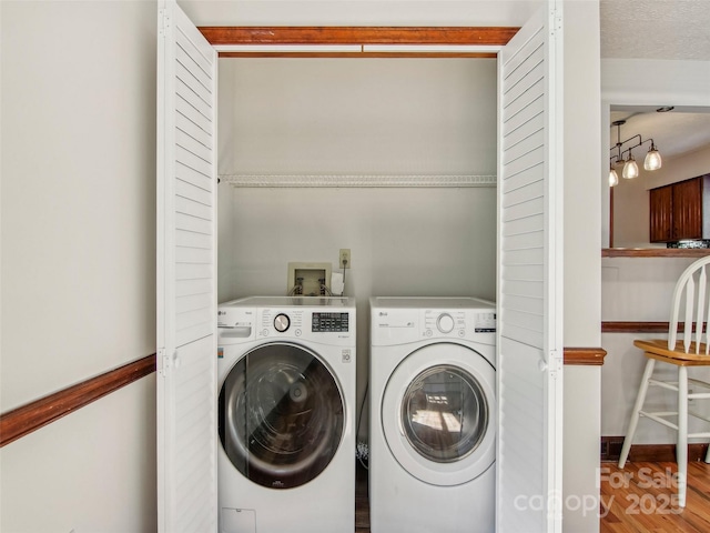clothes washing area with separate washer and dryer, wood finished floors, and laundry area