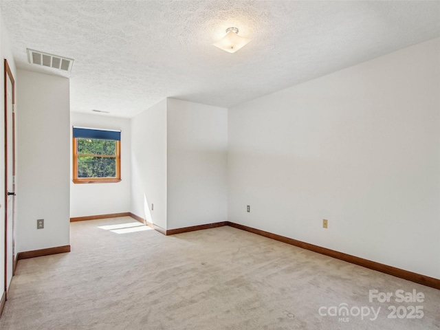 spare room with a textured ceiling, carpet, visible vents, and baseboards