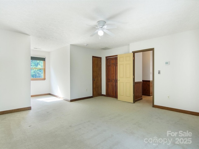 interior space with baseboards, a ceiling fan, and light carpet